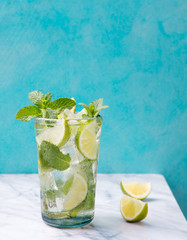 Mojito cocktail with lime and mint in highball glass on a marble table Blue background Copy space