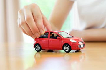 Business woman by a desk holding a toy car.