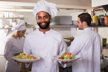 Crew of professional cooks working at restaurant