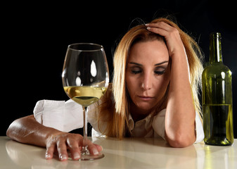 drunk alcoholic blond woman alone in wasted depressed drinking white wine glass suffering hangover