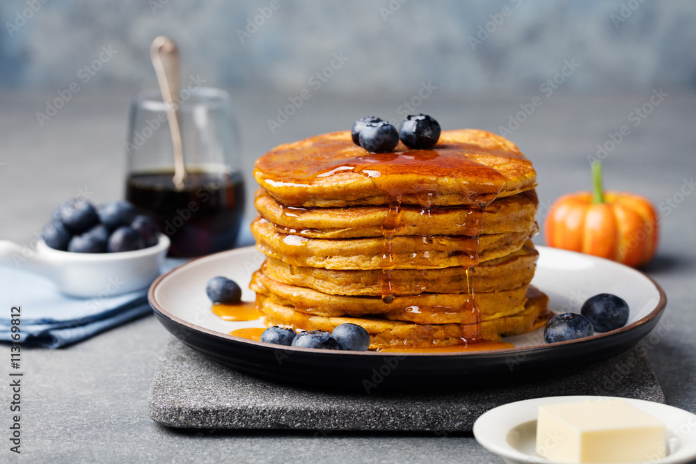 Wall mural pumpkin pancakes with maple syrup and blueberries on a plate. grey stone background