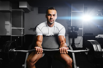Fototapeta na wymiar handsome bodybuilder pumping up hands in gym