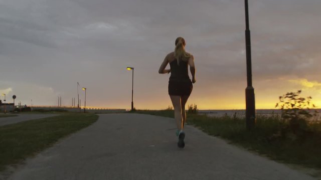 a young woman running at the ocean at sunset