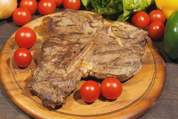 Grilled T bone steak with tomatoes, paprika onions and garnished