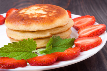 fritters on a plate with strawberries wooden background