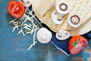 Ingredients for pizza (flat bread, cheese, tomatoes and mushroom