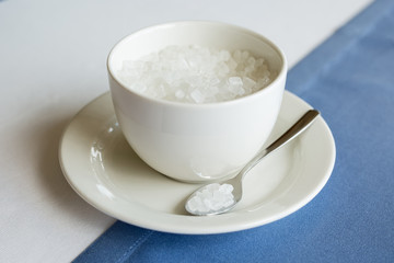 cup of refined sugar on the white- blue background
