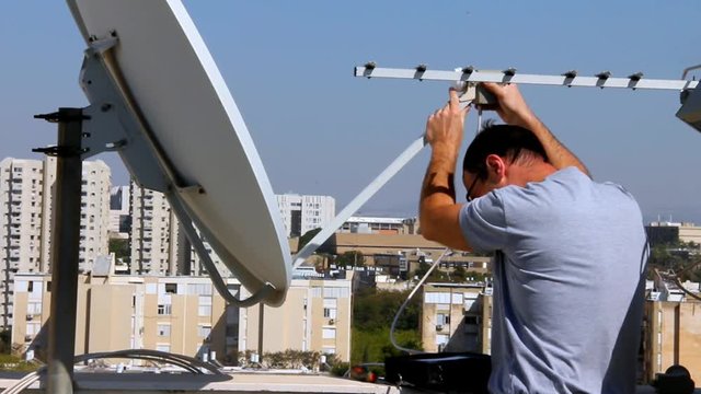 Technician fixing of receiving device of satellite dish in correct position