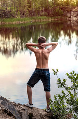 Fototapeta na wymiar Teenager near the lake standing on a rock