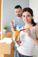 Portrait of happy smiling young couple painting interior wall of new house