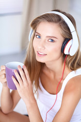 Portrait of beautiful woman in morning listening music sitting on bed at home