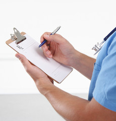 Male doctor writing prescription on clipboard