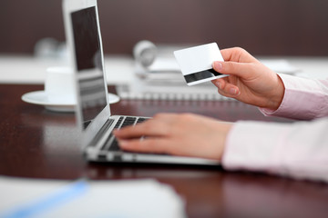 Close up of business woman hands using credit card and laptop computer