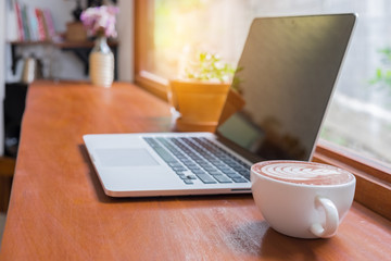 Laptop and coffee cup on wooden table