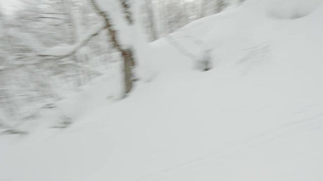 Snowboarder Big Jump Grabbing His Snowboard Indy Air into a Powder Snow Field at a Backcountry Snowboarding Spot