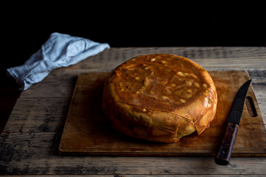 Timpano on wooden chopping board with knife