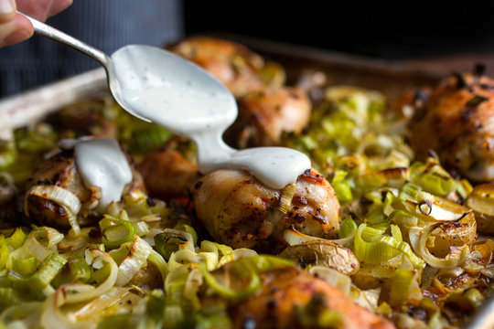 Person Spooning Sauce Over Meat In Dish