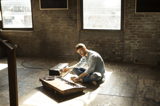 Young man playing synthesizer on floor