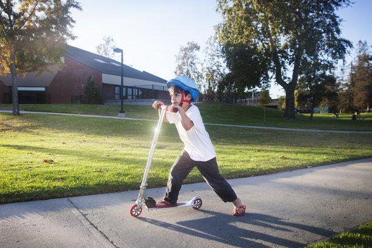 Boy (4-5) riding push scooter on footpath