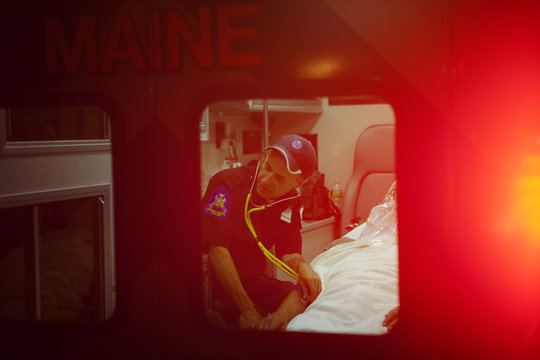 Paramedic checking heart rate of senior man in ambulance