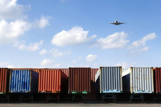 Airplane flying over row of freight containers