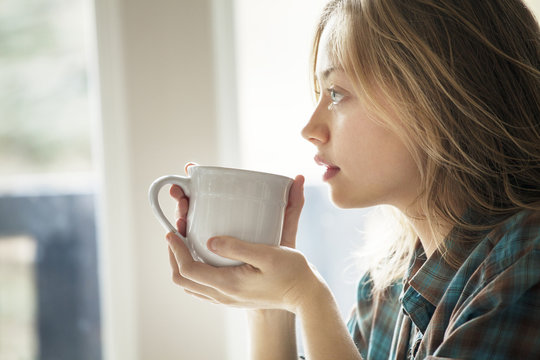 Close-up of woman holding coffee cup and looking away