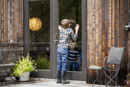 Little boy looking at his brother while kissing on door