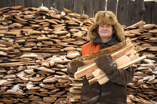 Man holding chopped wood in front of wood pile