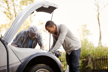 Father and son looking under hood of car