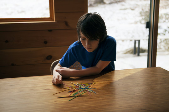 Boy (10-11) playing pick up sticks