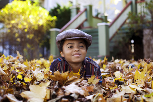 Boy (8-9) Playing In Fall Leaves
