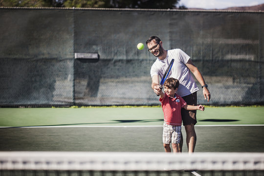 Father And Son Playing Tennis In Court