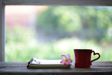 Red mug and notebooks with flower