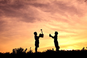 Silhouette children holding the tree and watering at sky sunset. Concept saves the world