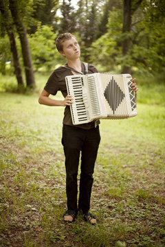 Young man playing accordion in forest
