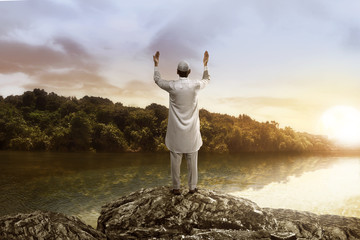 Young muslim man praying on the lake