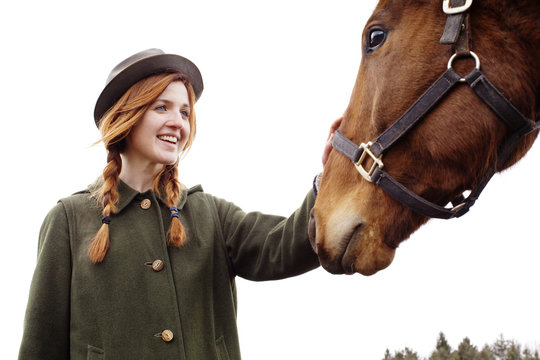 Young woman stroking horse muzzle