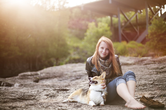 Young woman sitting with dog on rocks