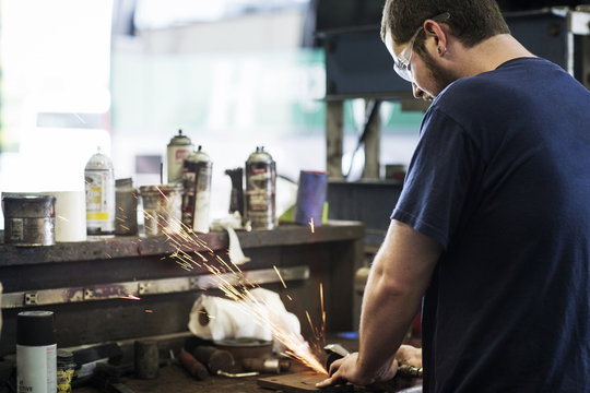 Mechanic grinding metal in workshop