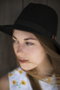 Woman wearing sun hat looking away against wood