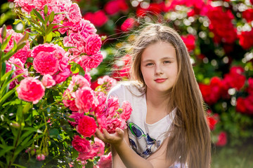 Obraz na płótnie Canvas Beautiful girl standing in the park of roses.