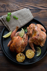 Two roasted chickens served in a frying pan, selective focus