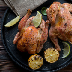 Close-up of two whole roasted chickens with lemon and lime