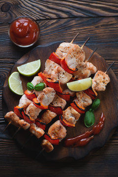 Barbecued chicken kebabs in a rustic wooden setting, top view