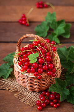 Basket with Red currant with leaves on a dark background.