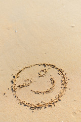 Top view on happy smiley face drawing on a sand.