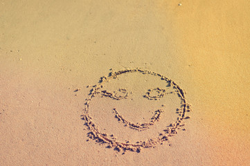 Top view on happy smiley face drawing on a sand.