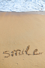 Abstract sign of word smile written, sand beach background