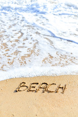 Beach sign on sandy ocean foam wave coastline