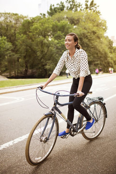 Woman cycling on road in central park